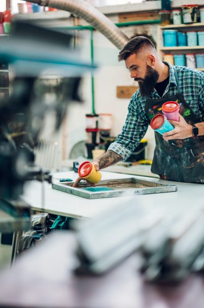 Male worker mixing colors for screen printing in a workshop